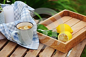 Summer breakfast in beautiful blooming garden. Tea with lemon, hydrangea flowers on wooden table with green background