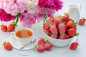 summer breakfast concept. tea, strawberries on a served table and lilacs