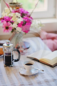 summer breakfast in cozy country house. Table with bouquet of flowers from own garden, french press with coffee and cookies.