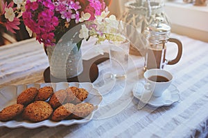 Summer breakfast in cozy country house. Table with bouquet of flowers from own garden, french press with coffee and cookies.