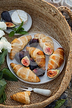 Summer breakfast with croissants and figs in a basket.
