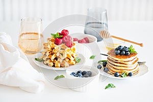 Summer breakfast. Homemade baked ricotta pancakes and Belgian waffles with fresh berries on white wooden table