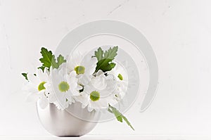 Summer bright chamomile bouquet in modern metallic glossy vase on soft light white background and wood table, copy space.