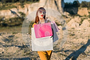 Summer bright portrait of beautiful young woman in yellow clothes and sunglasses, making air kiss to camera, while