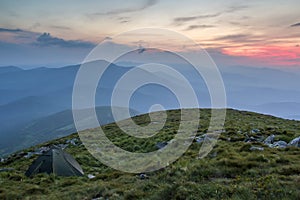 Summer camping in mountains at dawn. Tourist tent on round grass