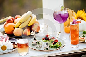 Summer catering buffet with canap snacks with eggplant, olives, herbs, tomatoes and meat. With cocktails and fruits
