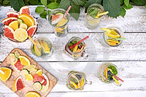 Summer champagne-based cocktails with fruits orange, lemon, lime, grapefruit and mint in glass mugs and glasses.