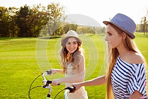 At summer cherful happy girls with hat riding bicycles on the park photo