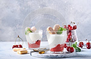 Summer cherry puff pastry with savoiardi cookies and cream cheese in glass on light grey background. Traditional tiramisu cake wit