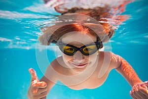 Summer child boy relax at aquapark. Summertime vacation. Little kid swim underwater in pool. Kid wearing summer goggles