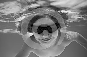 Summer child boy relax at aquapark. Summertime vacation. Little kid swim underwater in pool. Kid wearing summer goggles