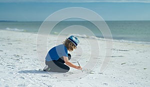 Summer child face. Cute kid kid drawing a on sand enjoying summer sea and dreaming. Funny little boy play on summer