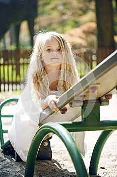 Summer, childhood, leisure, gesture and people concept - happy little girl playing on children playground