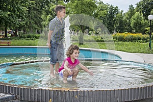 In the summer, children play in the fountain in the park.