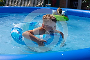 In summer, children swim in an inflatable pool with mugs and laugh. Children are enjoying the summer and splashing in