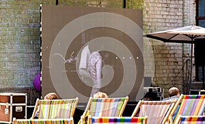 Summer cinema. People watch old movies sitting on beach chairs.