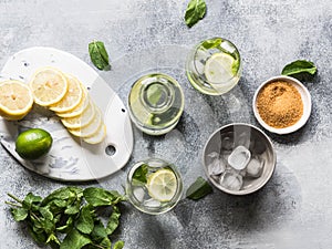 Summer citrus lemonade with ice in two bulging glasses, sugar in little white plate, slices of citrus on a ceramic white board and