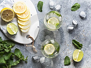 Summer citrus lemonade with ice in two bulging glasses, sugar in little white plate, slices of citrus on a ceramic white board and