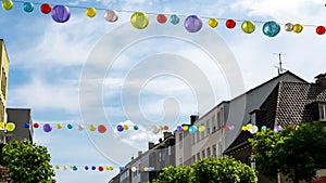 Summer in the city with colorful lampions in all rainbow colors over shopping street. Langenfeld, Germany