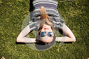 Summer close up portrait of pretty smiling young woman, laying on the grass, enjoy her vacation.