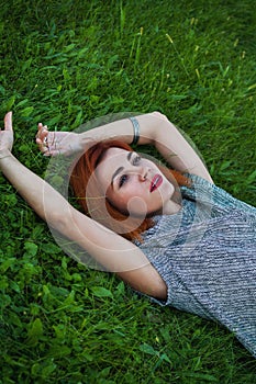 Summer close up portrait of pretty smiling young woman, laying on the grass, enjoy her vacation, natural make up red