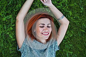 Summer close up portrait of pretty smiling young woman, laying on the grass, enjoy her vacation, natural make up red