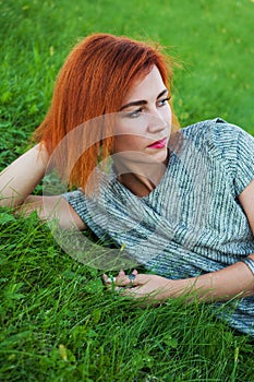 Summer close up portrait of pretty smiling young woman, laying on the grass, enjoy her vacation, natural make up red