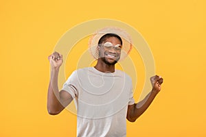 Summer clubbing. Joyful african american man dancing to favorite music over yellow studio background