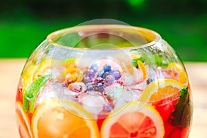 Summer cocktail. Fruit cocktail on green background. Citrus fruits, berries, strawberries, blueberries, mint, ice