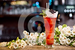 Summer cocktail with ice decorated with berries and mint on a wooden table