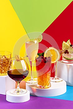 Summer cocktails in glasses with rum, gin, prosecco and liquors. Modern style still life on bright multi-colored geometric