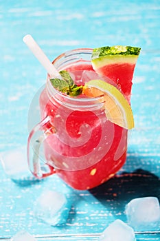 Summer cold drink with watermelon, mint and lemon on a wooden background