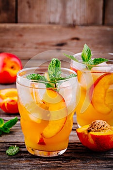 Summer cold drinks: homemade peach ice tea with ice cubes, and mint in glasses