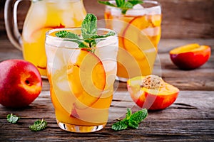Summer cold drinks: homemade peach ice tea with ice cubes, and mint in glasses