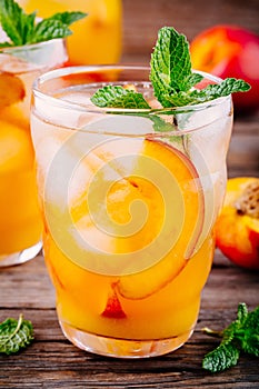 Summer cold drinks: homemade peach ice tea with ice cubes, and mint in glasses