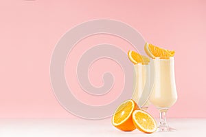 Summer cold fresh milk cocktail of orange with juicy pieces fruit on white wood board and cute soft pastel pink wall, copy space.