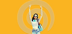 Summer colorful portrait of stylish modern young woman having fun listening to music in headphones posing on orange background