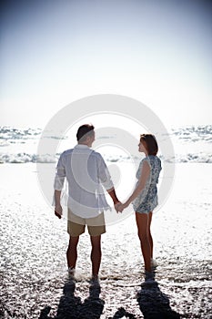 With summer comes the romance. Rearview of a happy mature couple walking hand in hand on the beach.