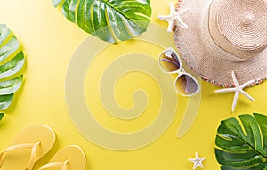 Summer composition concept made from starfish, beach hat, flip flop and monstera leaf on pastel yellow background