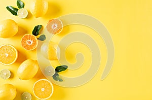 Summer composition made from oranges, lemon and green leaves on pastel yellow background. Fruit minimal concept. Flat lay, top