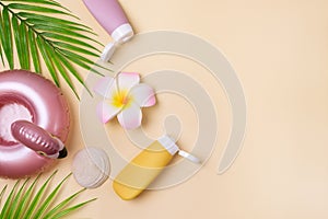 Summer composition with sunblock lotion bottles, palm leaf, sea shells and plumeria on pink background copy space Summer vacation