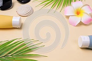 Summer composition with sunblock lotion bottles, palm leaf, sea shells and plumeria on pink background copy space Summer vacation