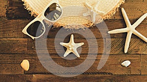 Summer composition with sunglasses, straw hat, starfishes and shells on wooden table.