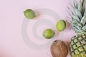 Summer composition. Tropical fruits - pineapple, coconut, lime on pastel pink background. Summer concept. Flat lay, top view, copy