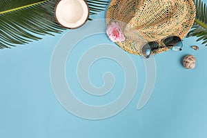 Summer composition. Tropical leaves, hat, coconut on blue background. Summer concept.