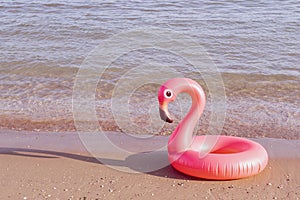 Summer concept background. Pink inflatable flamingo in blue ocean water for sea summer beach background. Pool float party