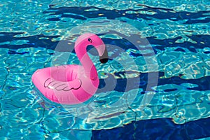 Summer concept background. Pink inflatable flamingo in pool water for summer beach background. Pool float party photo