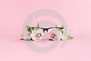 Summer concept of beach sunglasses with flowers instead of glasses on a pink background. Summer vacation and enjoyment