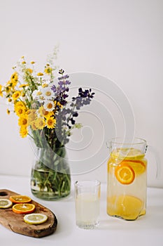 Summer concept. Bouquet of wild natural flowers. Homemade lemonade with orange and lemon. Healthy  fresh cool beverage