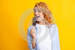 Summer concept. Glad positive woman holds tasty frozen ice cream, enjoys eating delicious cold dessert, poses on yellow